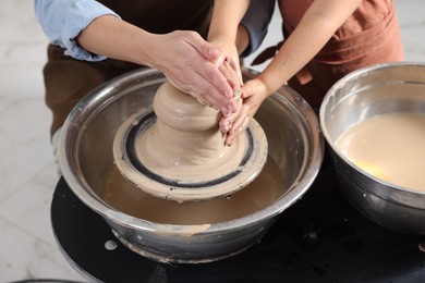 Photo of Hobby and craft. Mother with her daughter making pottery indoors, closeup