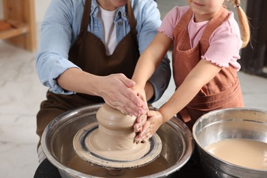 Photo of Hobby and craft. Mother with her daughter making pottery indoors, closeup