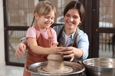 Photo of Hobby and craft. Smiling mother with her daughter making pottery indoors