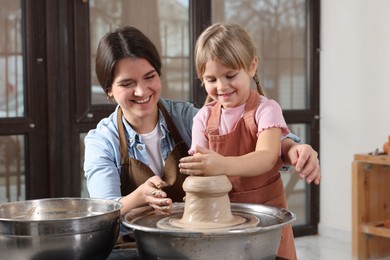 Photo of Hobby and craft. Smiling mother with her daughter making pottery indoors