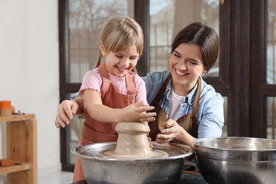 Photo of Hobby and craft. Smiling mother with her daughter making pottery indoors