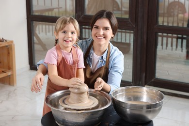 Photo of Hobby and craft. Smiling mother with her daughter making pottery indoors