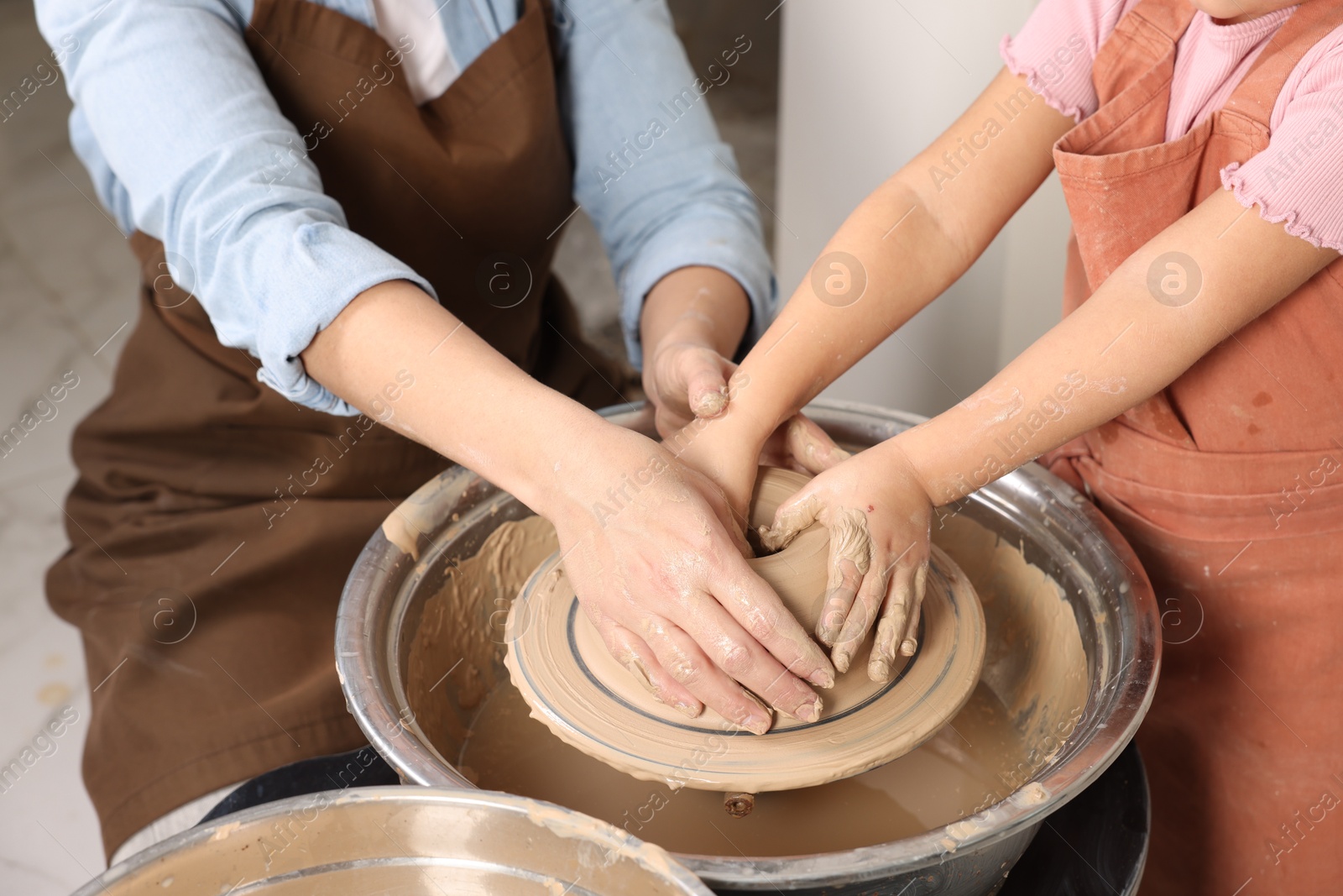 Photo of Hobby and craft. Mother with her daughter making pottery indoors, closeup