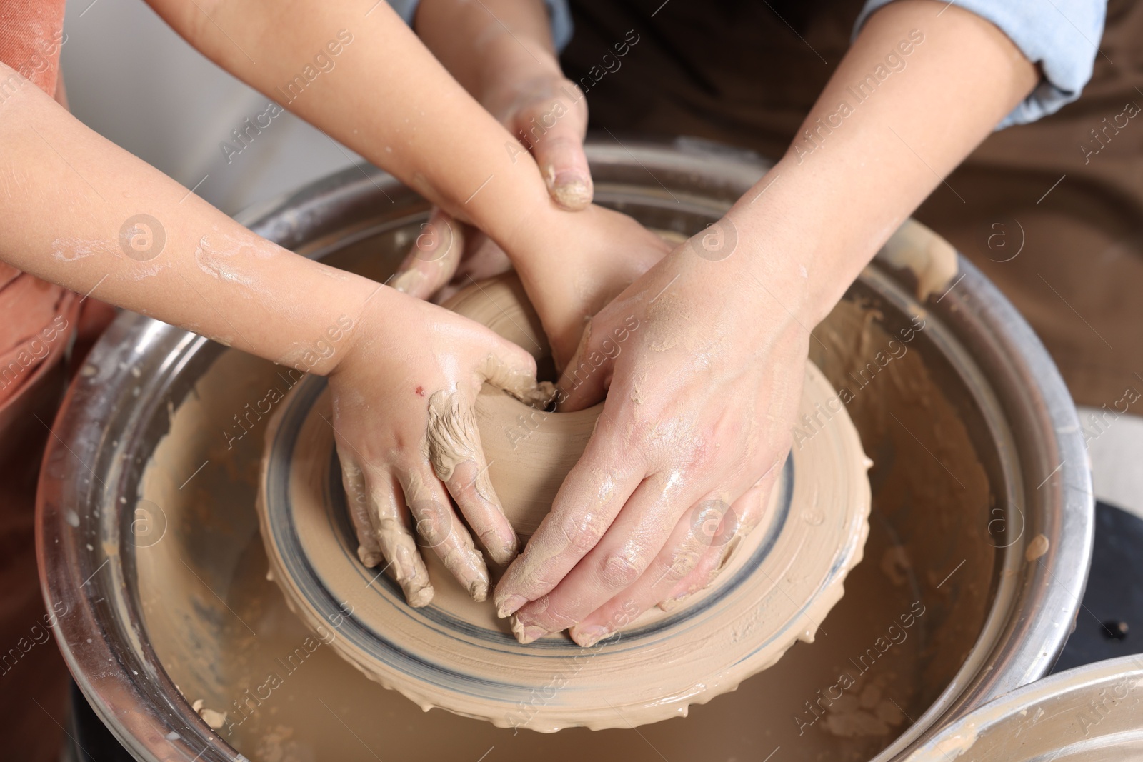 Photo of Hobby and craft. Mother with her daughter making pottery indoors, closeup