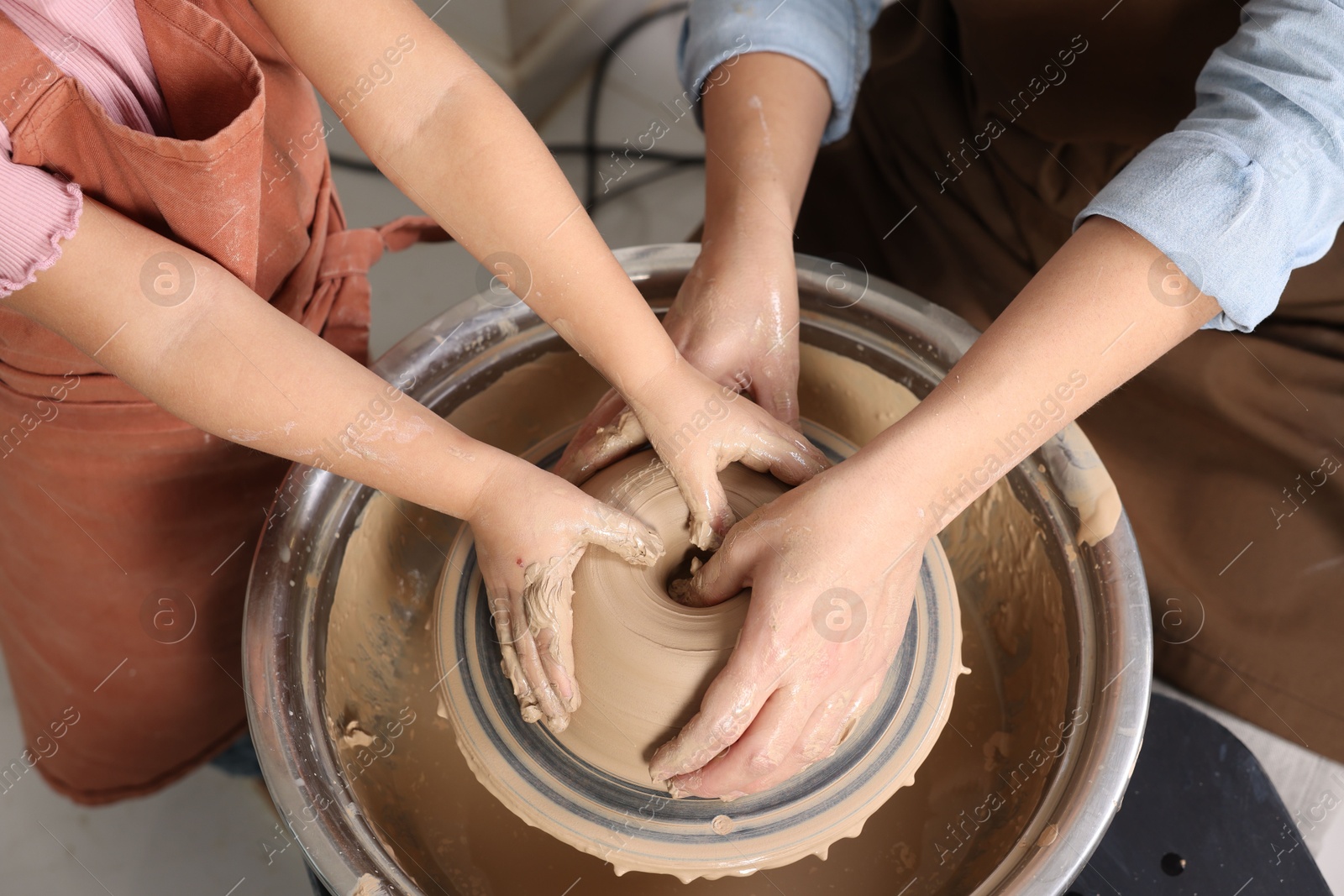 Photo of Hobby and craft. Mother with her daughter making pottery indoors, closeup