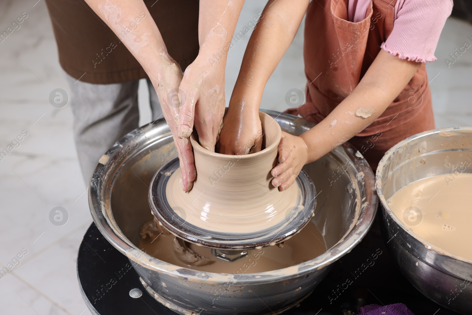 Photo of Hobby and craft. Mother with her daughter making pottery indoors, closeup