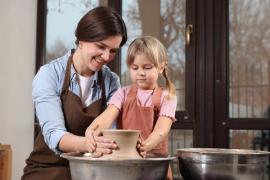 Photo of Hobby and craft. Smiling mother with her daughter making pottery indoors