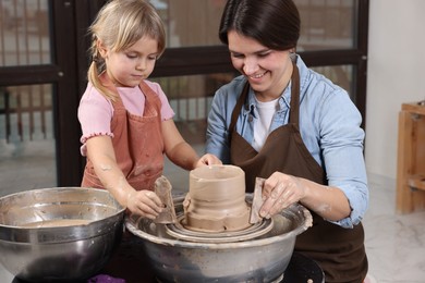 Photo of Hobby and craft. Smiling mother with her daughter making pottery indoors