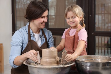 Photo of Hobby and craft. Smiling mother with her daughter making pottery indoors