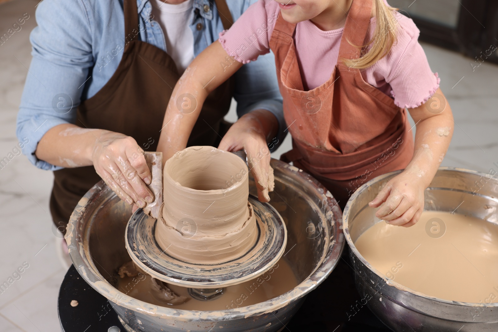 Photo of Hobby and craft. Mother with her daughter making pottery indoors, closeup