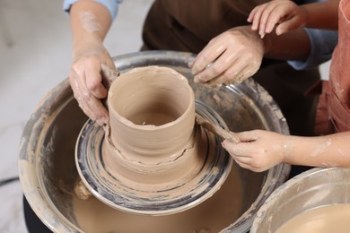 Photo of Hobby and craft. Mother with her daughter making pottery indoors, closeup