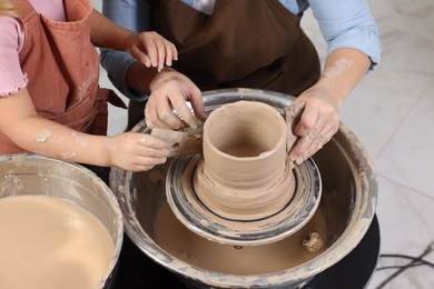 Photo of Hobby and craft. Mother with her daughter making pottery indoors, closeup