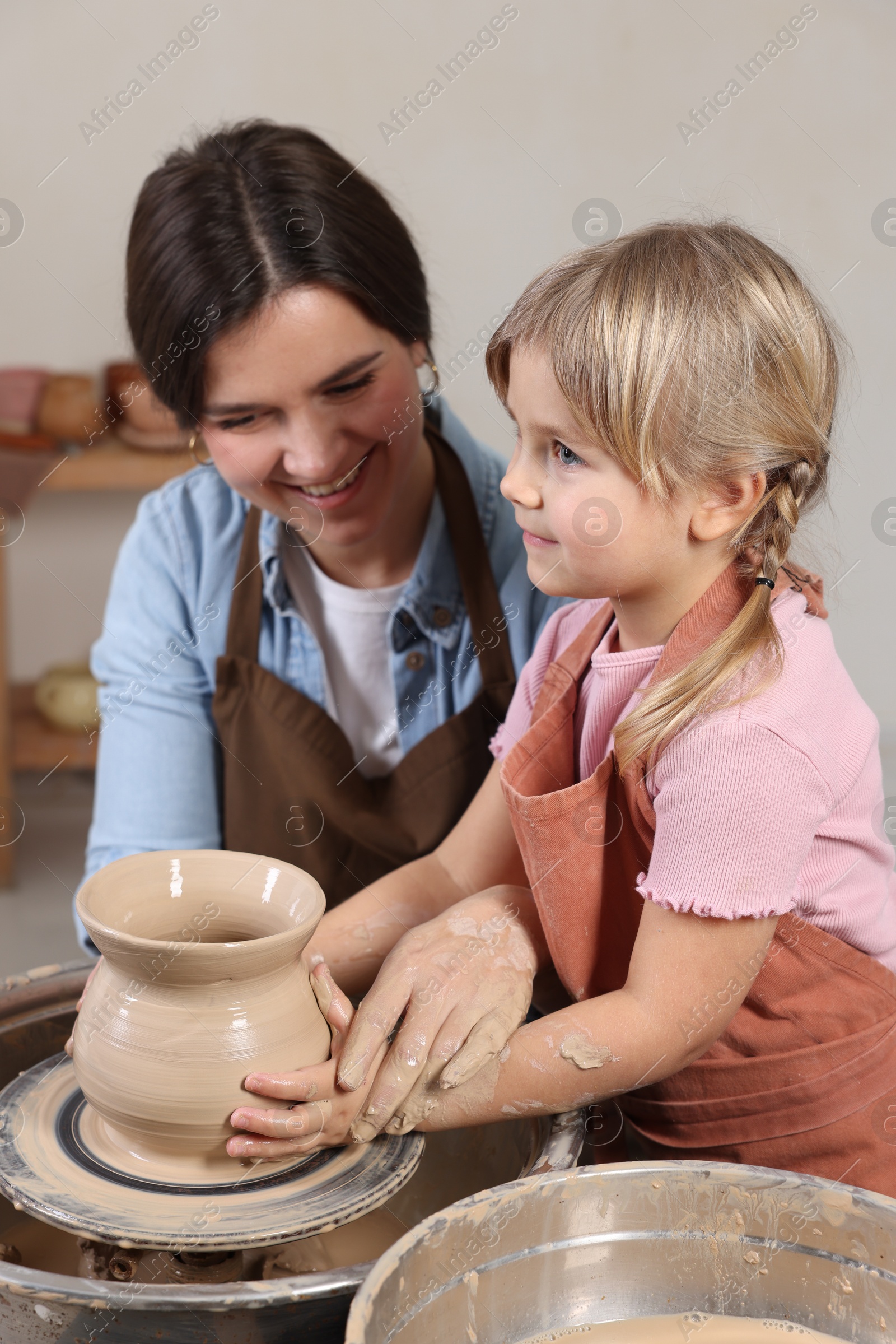 Photo of Hobby and craft. Smiling mother with her daughter making pottery indoors