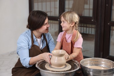 Photo of Hobby and craft. Smiling mother with her daughter making pottery indoors