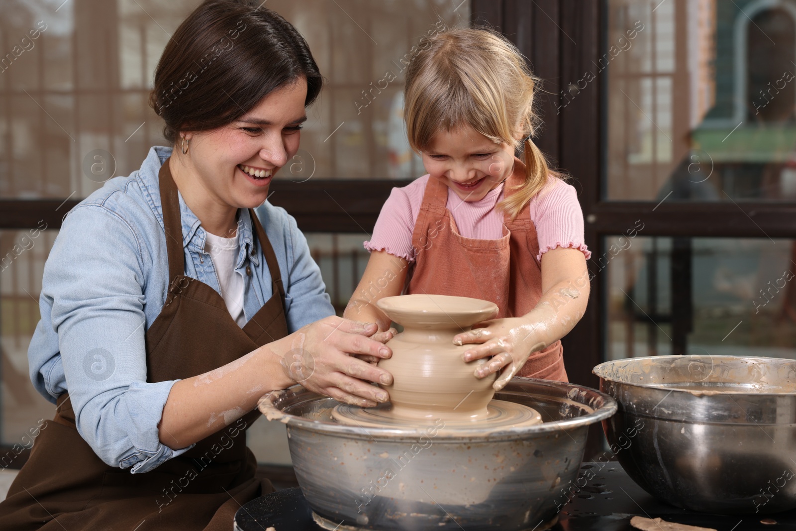 Photo of Hobby and craft. Smiling mother with her daughter making pottery indoors