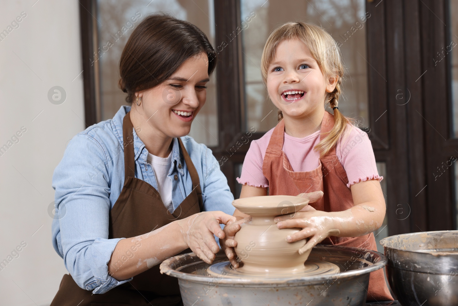 Photo of Hobby and craft. Smiling mother with her daughter making pottery indoors