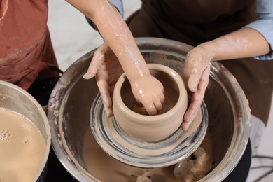 Photo of Hobby and craft. Mother with her daughter making pottery indoors, closeup