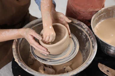 Photo of Hobby and craft. Mother with her daughter making pottery indoors, closeup