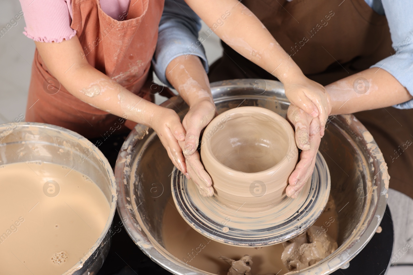 Photo of Hobby and craft. Mother with her daughter making pottery indoors, closeup