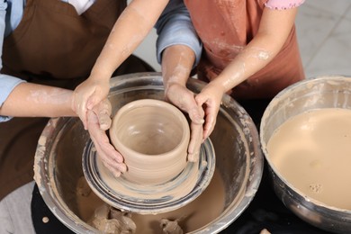 Photo of Hobby and craft. Mother with her daughter making pottery indoors, closeup