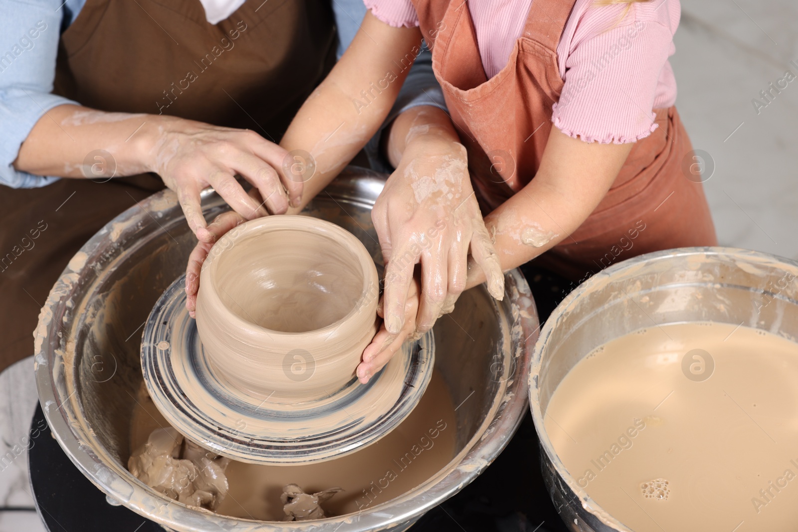 Photo of Hobby and craft. Mother with her daughter making pottery indoors, closeup