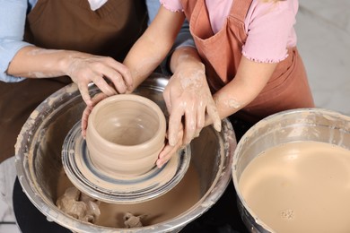 Photo of Hobby and craft. Mother with her daughter making pottery indoors, closeup