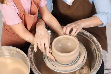 Photo of Hobby and craft. Mother with her daughter making pottery indoors, closeup