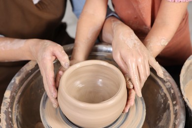 Photo of Hobby and craft. Mother with her daughter making pottery indoors, closeup