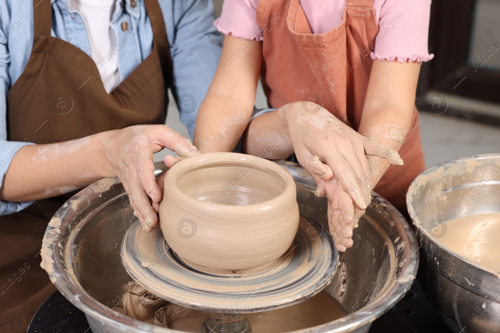 Photo of Hobby and craft. Mother with her daughter making pottery indoors, closeup