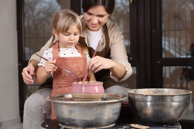 Photo of Hobby and craft. Smiling mother with her daughter making pottery indoors