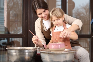 Photo of Hobby and craft. Smiling mother with her daughter making pottery indoors