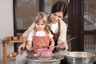 Photo of Hobby and craft. Smiling mother with her daughter making pottery indoors