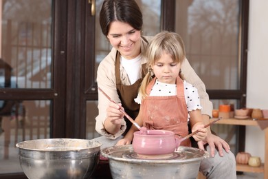 Photo of Hobby and craft. Smiling mother with her daughter making pottery indoors