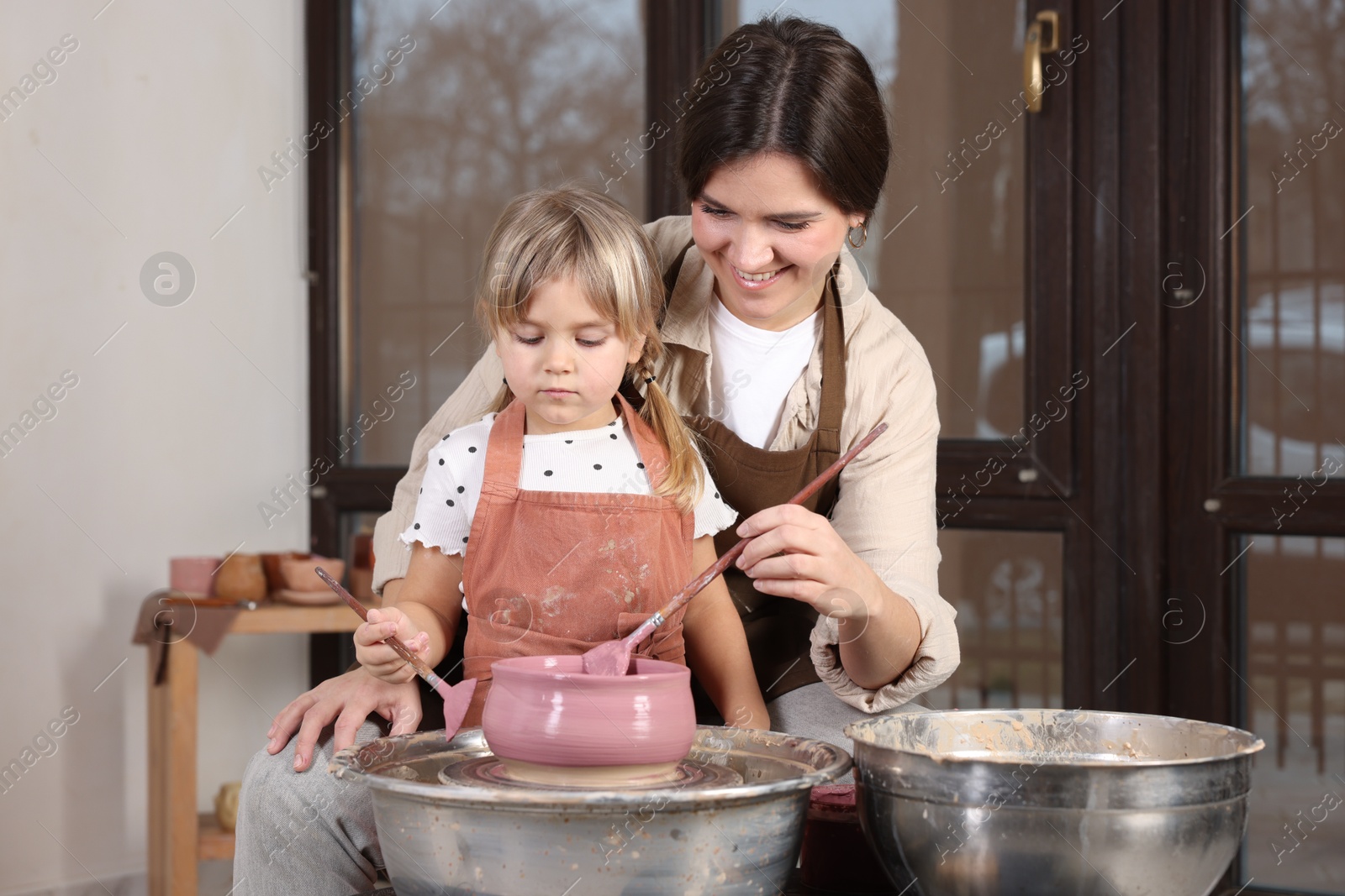 Photo of Hobby and craft. Smiling mother with her daughter making pottery indoors