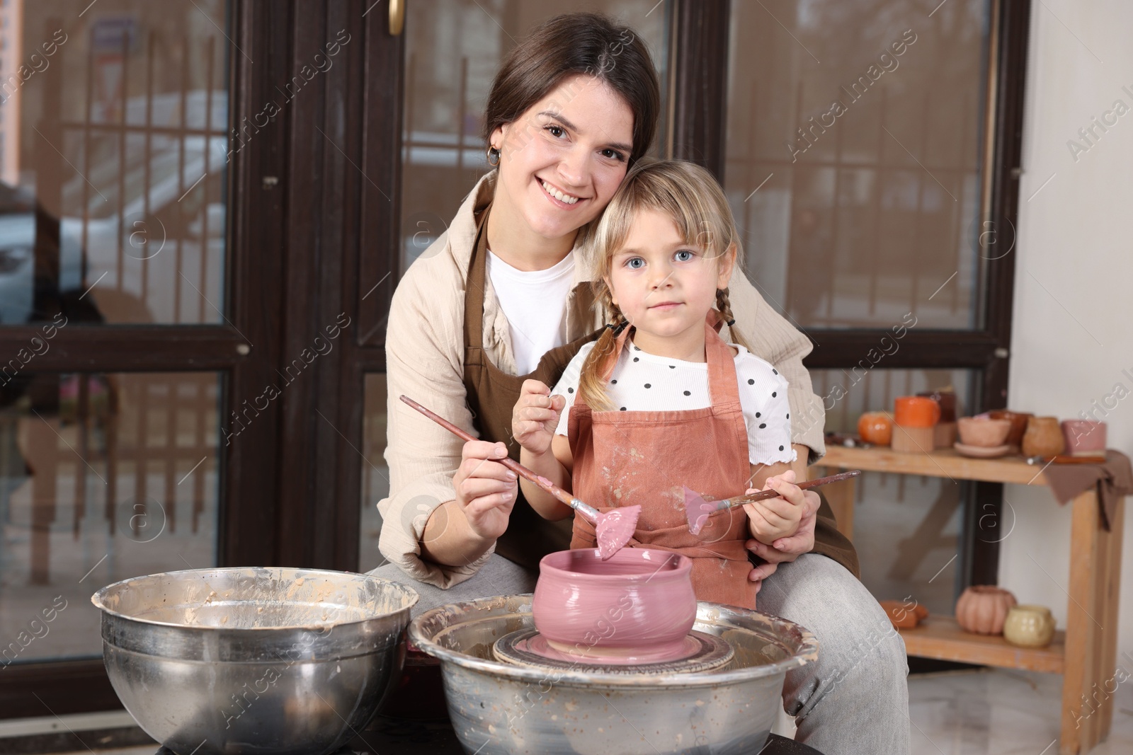 Photo of Hobby and craft. Smiling mother with her daughter making pottery indoors