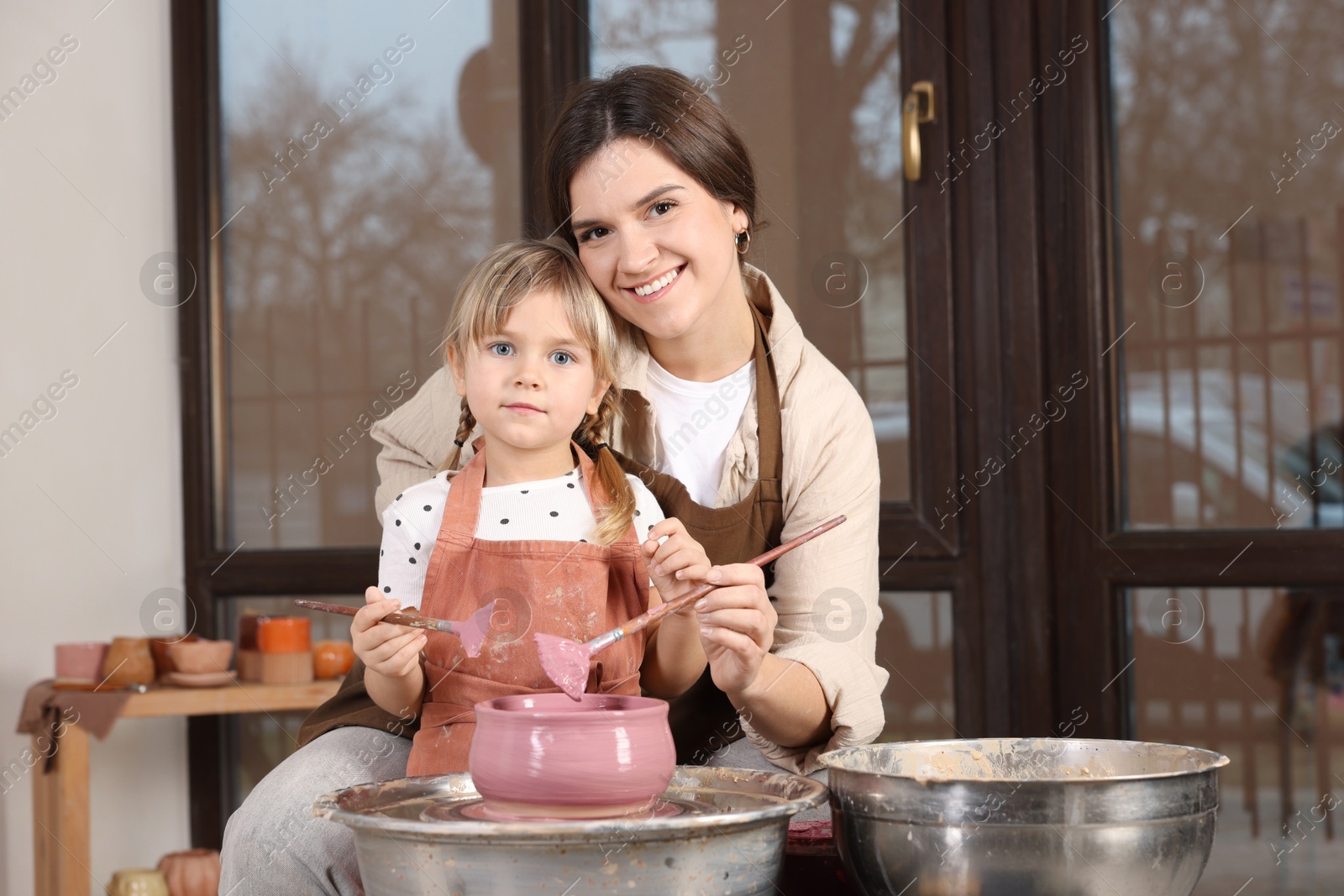 Photo of Hobby and craft. Smiling mother with her daughter making pottery indoors