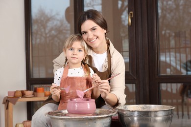 Photo of Hobby and craft. Smiling mother with her daughter making pottery indoors