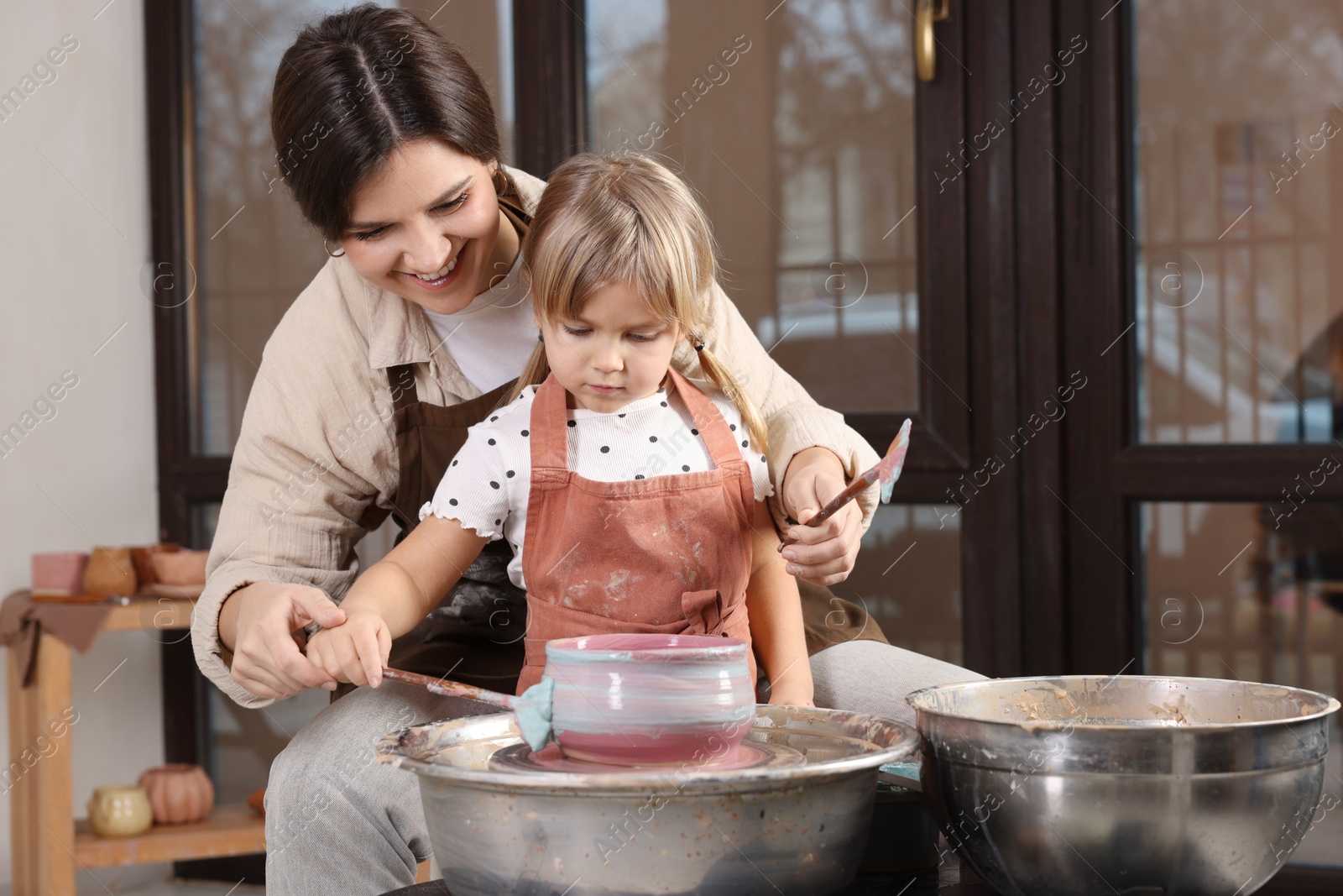 Photo of Hobby and craft. Smiling mother with her daughter making pottery indoors