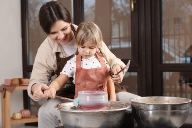 Photo of Hobby and craft. Smiling mother with her daughter making pottery indoors