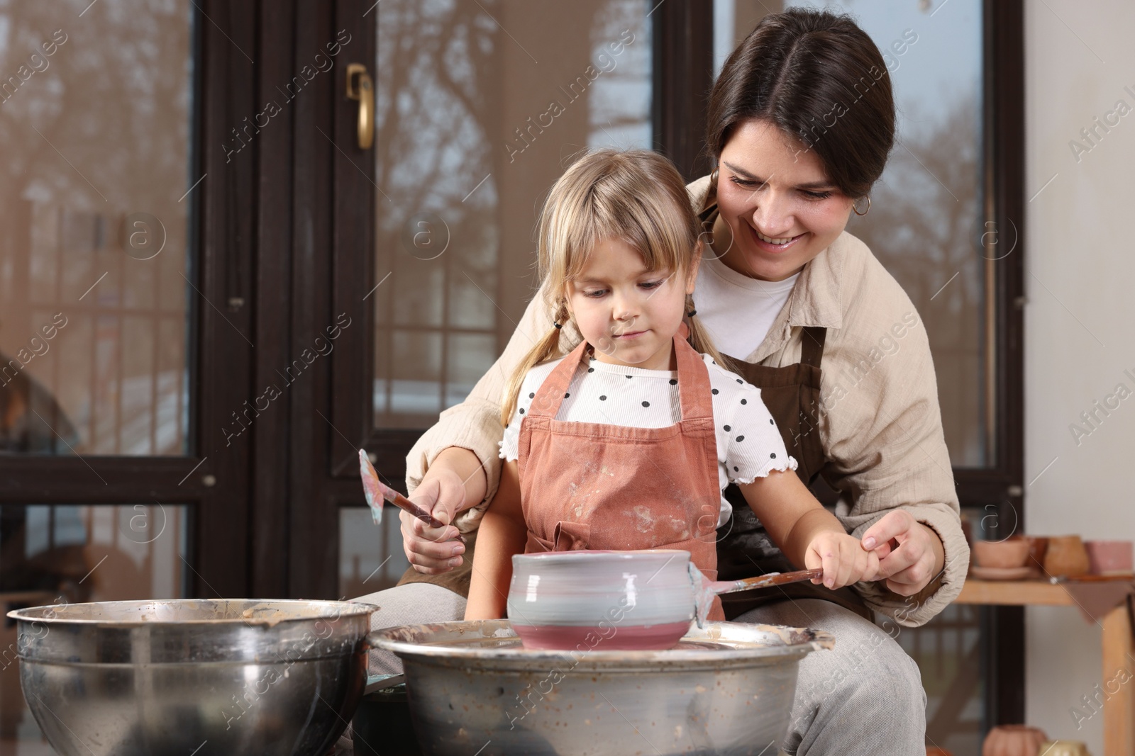 Photo of Hobby and craft. Smiling mother with her daughter making pottery indoors