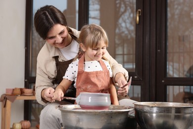 Hobby and craft. Smiling mother with her daughter making pottery indoors