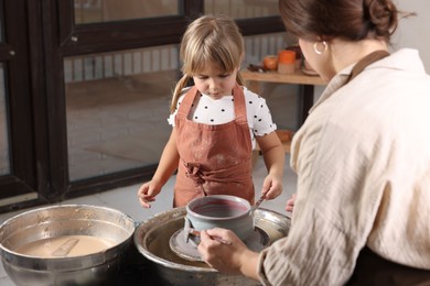 Photo of Hobby and craft. Daughter with her mother making pottery indoors