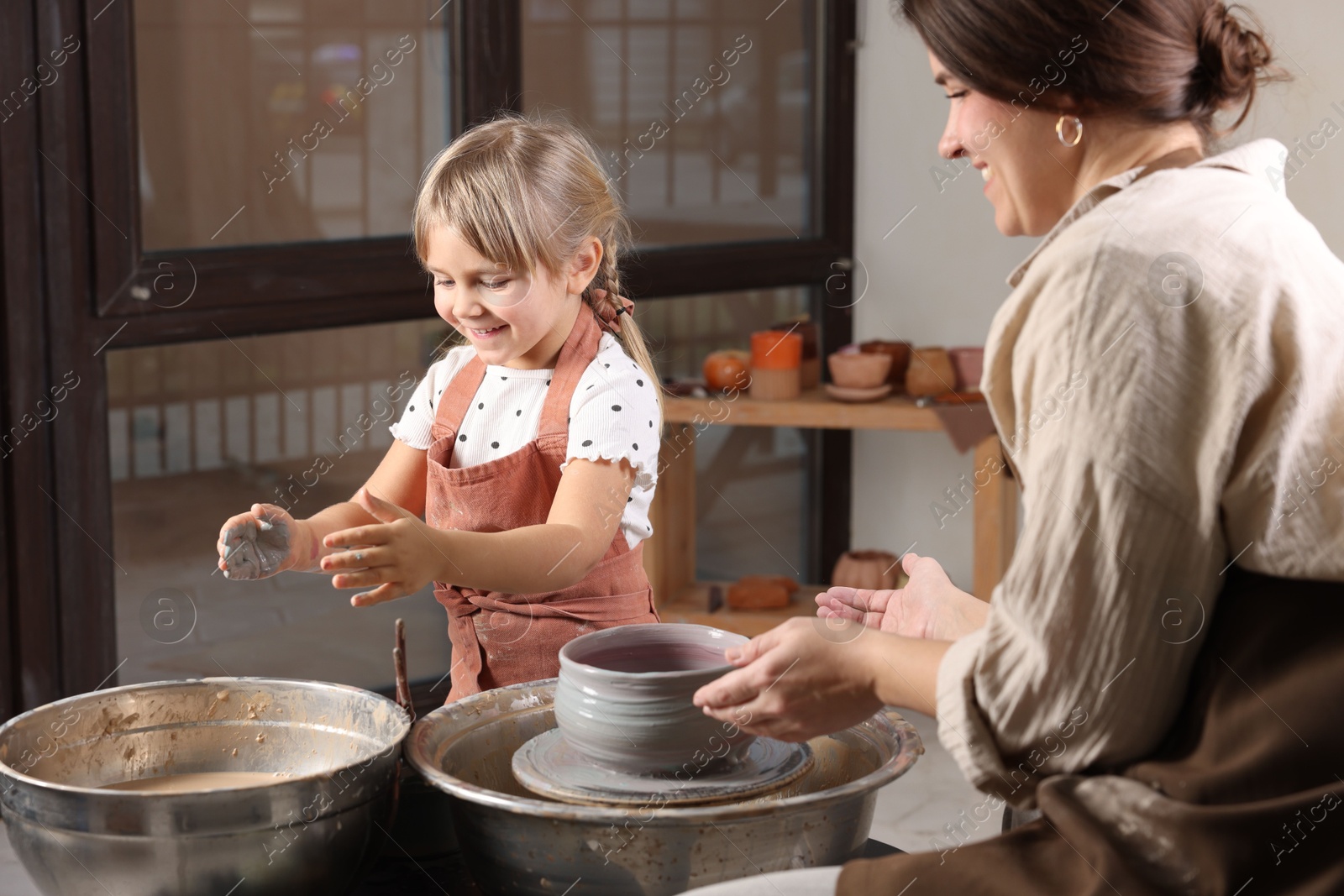 Photo of Hobby and craft. Smiling daughter with her mother making pottery indoors