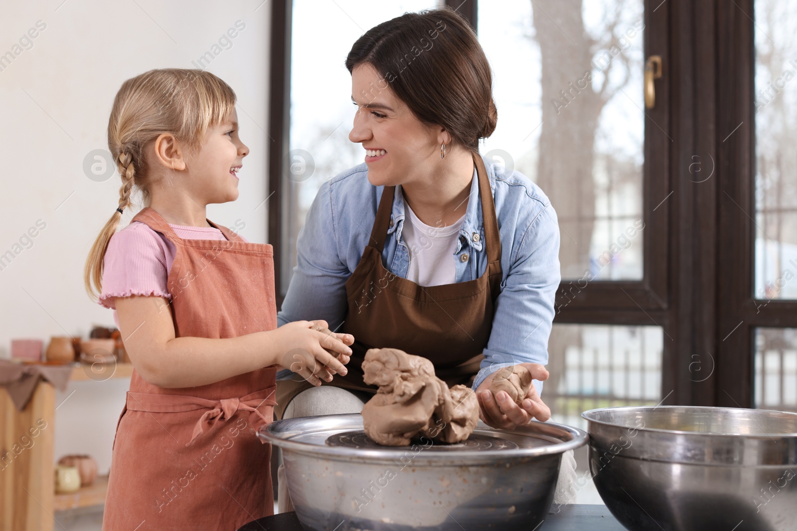 Photo of Hobby and craft. Smiling mother with her daughter making pottery indoors