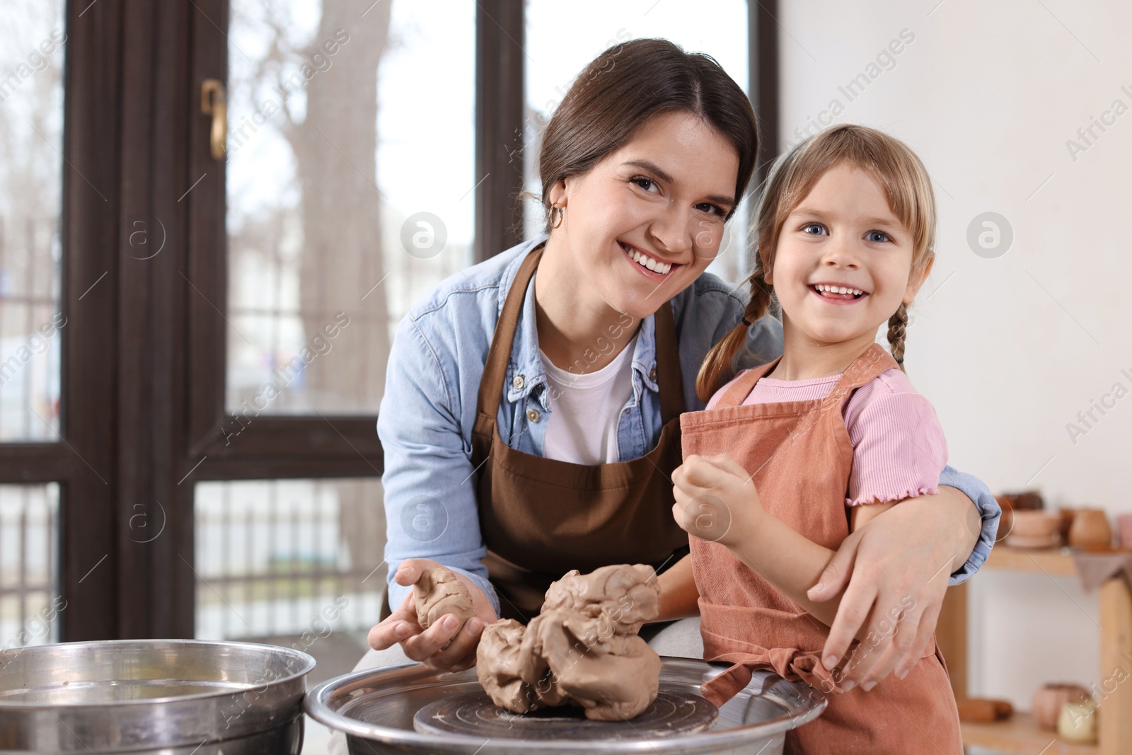 Photo of Hobby and craft. Smiling mother with her daughter making pottery indoors