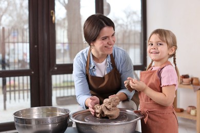 Photo of Hobby and craft. Smiling mother with her daughter making pottery indoors