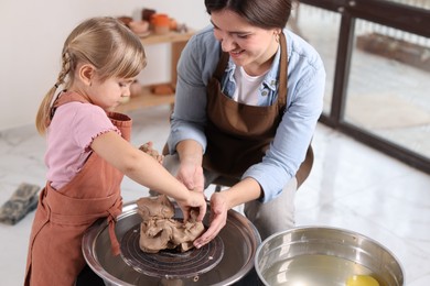 Photo of Hobby and craft. Smiling mother with her daughter making pottery indoors