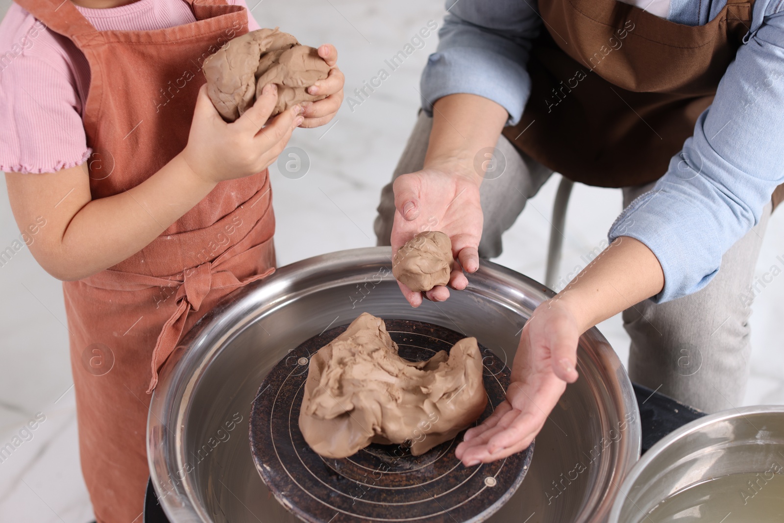 Photo of Hobby and craft. Mother with her daughter making pottery indoors, closeup