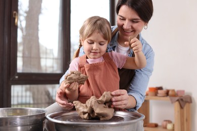 Photo of Hobby and craft. Smiling mother with her daughter making pottery indoors