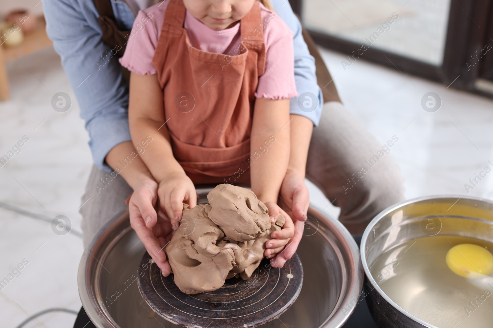 Photo of Hobby and craft. Mother with her daughter making pottery indoors, closeup